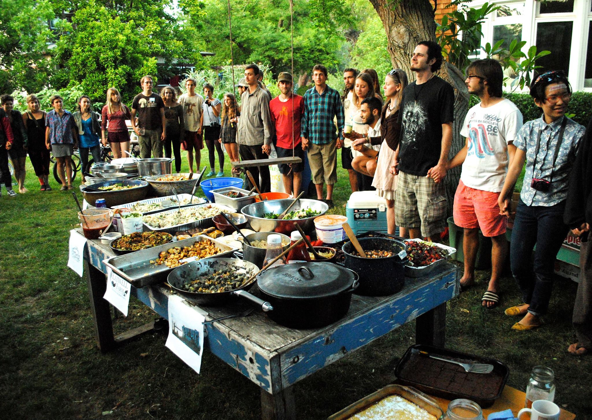 A group of WestCo attendees stand in a circle to say a community prayer over their collective dinner.