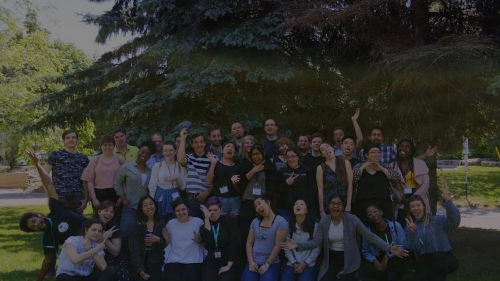 Group of co-opers make silly faces in front of pine trees