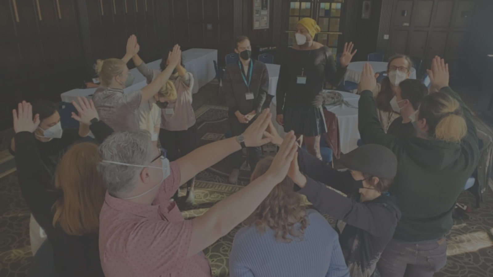 workshop image of groups of 2 people meeting hands above their head and one person in between. 